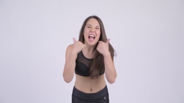 Junge glückliche Frau gibt Daumen nach oben und sieht aufgeregt bereit für das Fitnessstudio — Stockvideo