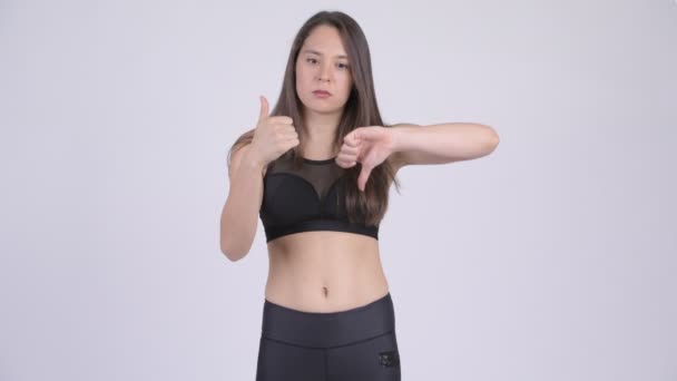Jonge vrouw kiezen tussen duimen omhoog en duimen naar beneden klaar voor sportschool — Stockvideo