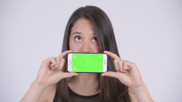 Joven feliz mujer multiétnica pensando mientras muestra el teléfono listo para el gimnasio — Vídeo de stock