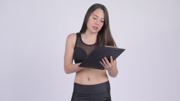 Молода щаслива жінка розмовляє під час читання на кишені готовий для спортзалу — стокове відео