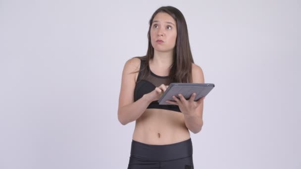 Молодая счастливая многонациональная женщина думает, используя цифровой планшет готов к тренажерному залу — стоковое видео
