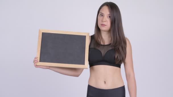 年轻的压力大的女子拿着黑板, 竖起大拇指准备去健身房 — 图库视频影像