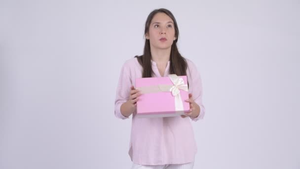 Junge multiethnische Geschäftsfrau denkt, während sie eine Geschenkschachtel hält — Stockvideo