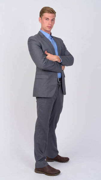 Profile view of young handsome blonde businessman with arms crossed
