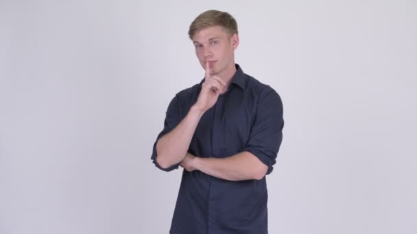 Молодой счастливый блондин-бизнесмен с пальцем на губах — стоковое видео