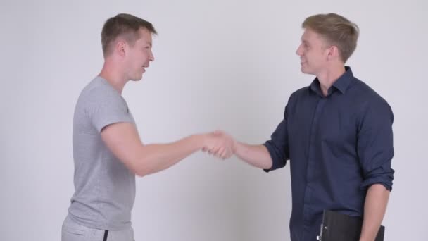 Dos jóvenes felices y guapos hombres estrechando las manos juntos — Vídeos de Stock