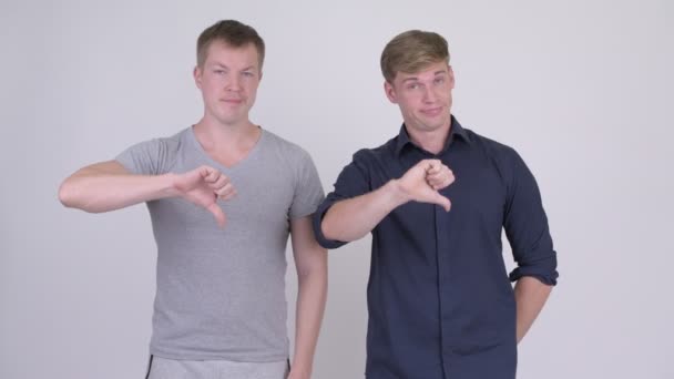 Två stressade unga män att ge tummen ner tillsammans — Stockvideo