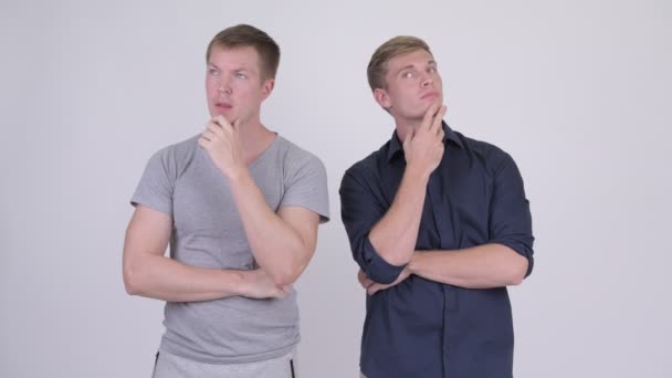Deux jeunes hommes beaux et heureux pensant ensemble — Video