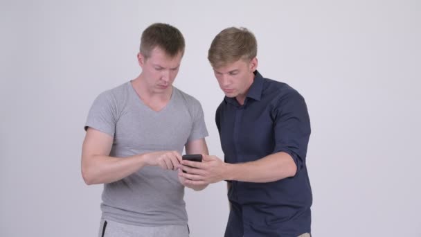 Two stressed young men using phone and getting bad news together — Stock Video