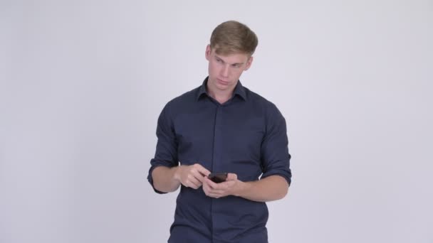 Glücklich junge gutaussehende Geschäftsmann denken, während mit dem Telefon — Stockvideo
