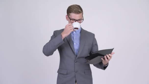 年轻的商人一边喝咖啡, 一边看眼镜看书 — 图库视频影像