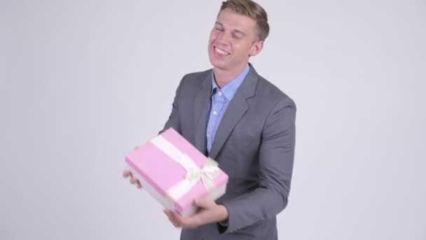 Счастливый молодой привлекательный бизнесмен держит подарочную коробку и показывает большие пальцы вверх — стоковое видео