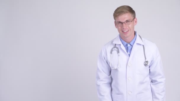 Happy young handsome man doctor showing something — Stock Video