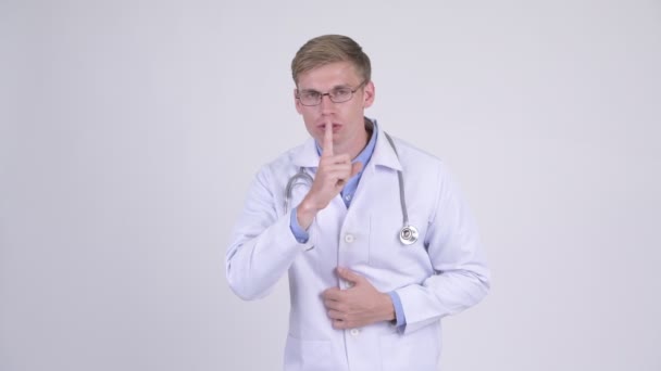 Serio joven guapo médico hombre con el dedo en los labios — Vídeos de Stock