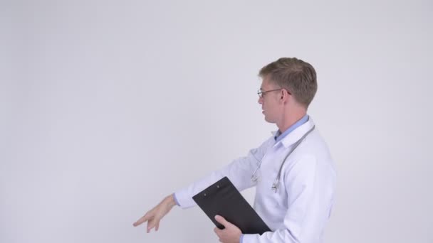 Rückansicht eines jungen Mannes Arzt denkt und zeigt mit dem Finger — Stockvideo