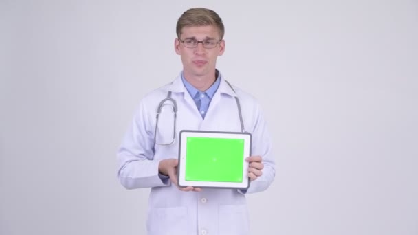 Jovem feliz bonito homem médico falando ao mostrar tablet digital — Vídeo de Stock