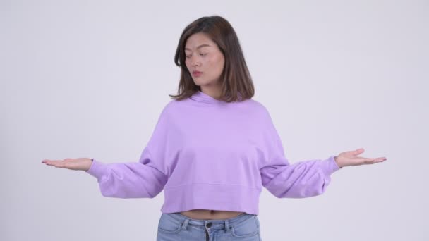Junge glückliche asiatische Frau vergleicht etwas — Stockvideo