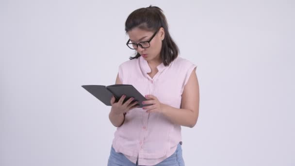 Young beautiful Asian businesswoman covering face with book — Stock Video