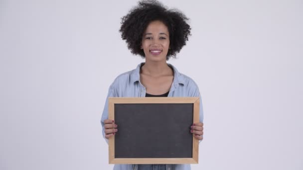 Joven mujer africana feliz sosteniendo pizarra — Vídeo de stock