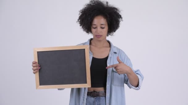 Молодая африканская женщина держит доску и показывает пальцами вниз — стоковое видео