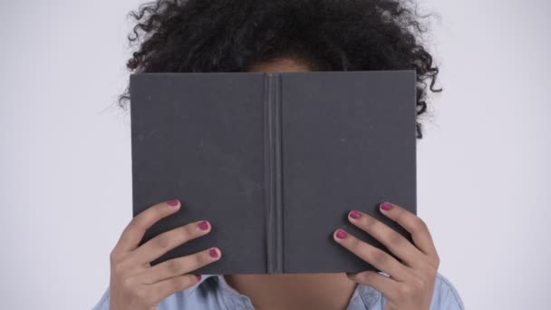 Rosto da jovem mulher africana com óculos cobrindo rosto com livro — Vídeo de Stock