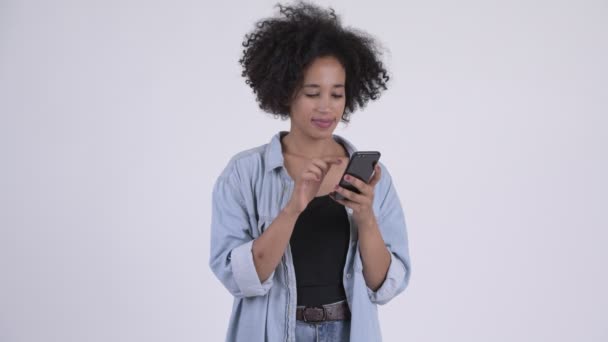 Joven mujer africana feliz usando el teléfono y mirando sorprendido — Vídeo de stock