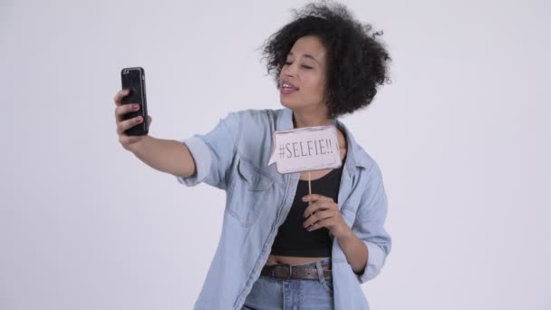 Unga glada afrikanska kvinnan tar selfie med papper skylt — Stockvideo