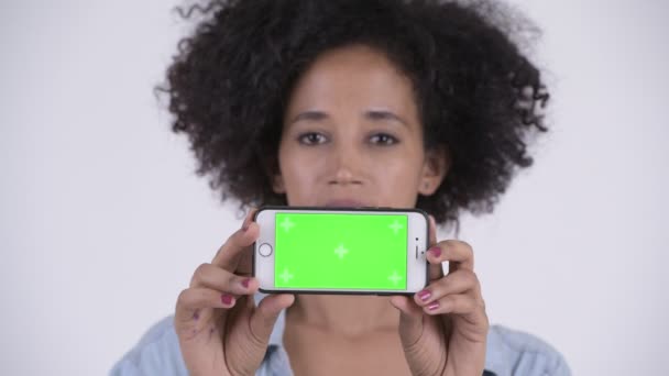 Gezicht van jonge gelukkig Afrikaanse vrouw denken terwijl het tonen van de telefoon — Stockvideo