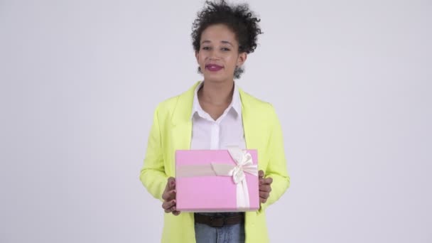 Glada unga vackra afrikanska affärskvinna tänkande medan du håller presentbox — Stockvideo