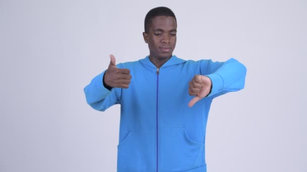 Jonge Afrikaanse man kiezen tussen duim omhoog verward en duim omlaag — Stockvideo