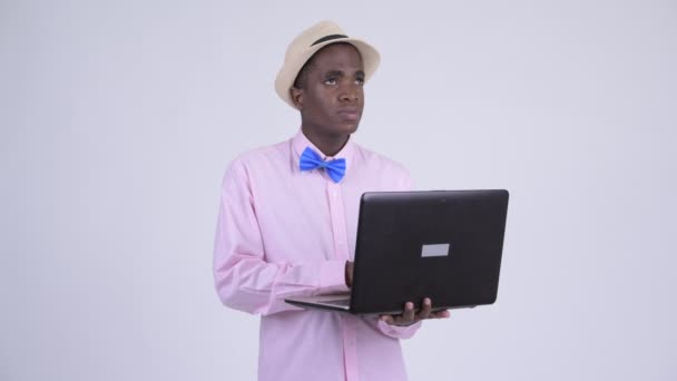 Junger glücklicher afrikanischer Touristenmann denkt während er Laptop benutzt — Stockvideo