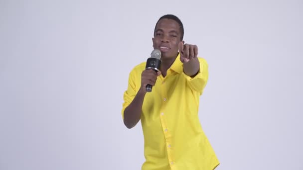 Jovem empresário africano feliz cantando com microfone — Vídeo de Stock