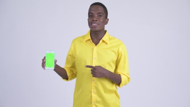 Joven empresario africano feliz mostrando el teléfono y dando pulgares hacia arriba — Vídeo de stock