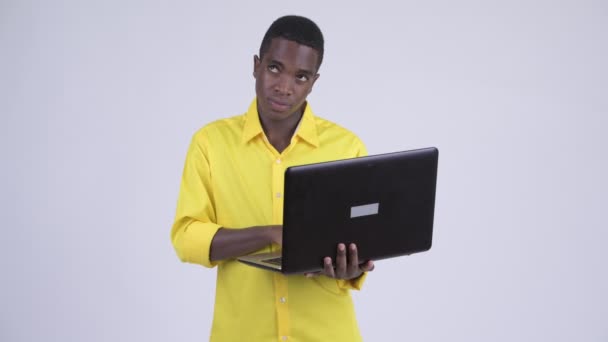Joven empresario africano feliz pensando mientras usa el ordenador portátil — Vídeos de Stock