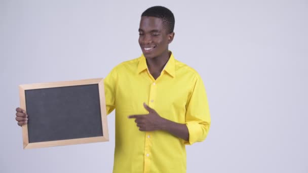 Молодой счастливый африканский бизнесмен держит доску и показывает большие пальцы — стоковое видео