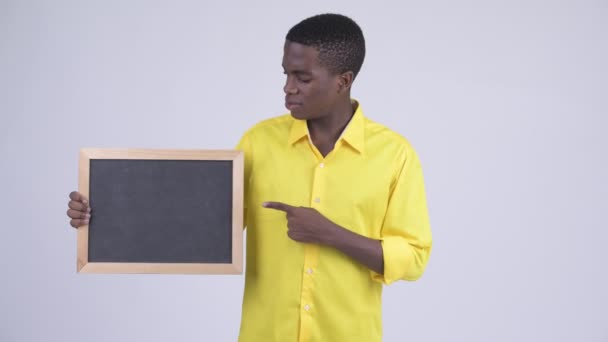 Young benadrukt Afrikaanse zakenman holding blackboard en duimen neer geven — Stockvideo