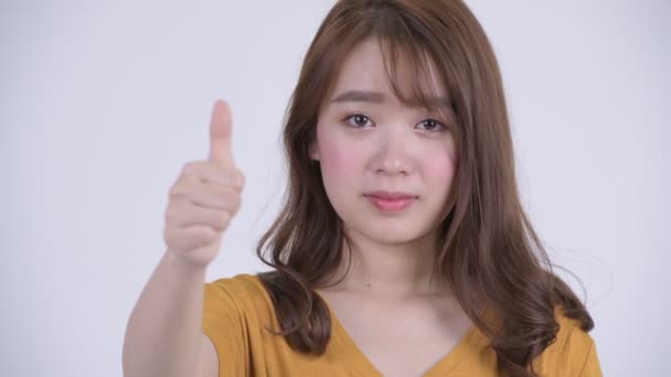 Gezicht van gelukkige jonge mooie Aziatische vrouw geven duimen omhoog — Stockvideo