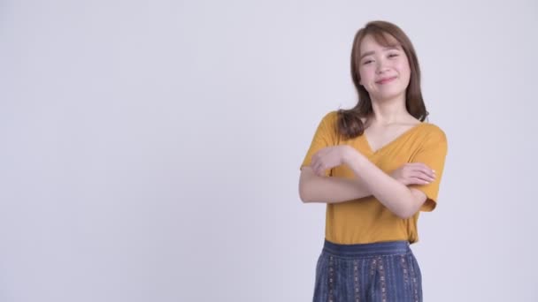 Hossz-szelvény nézet boldog fiatal gyönyörű ázsiai nő, mosolygós, keresztbe — Stock videók