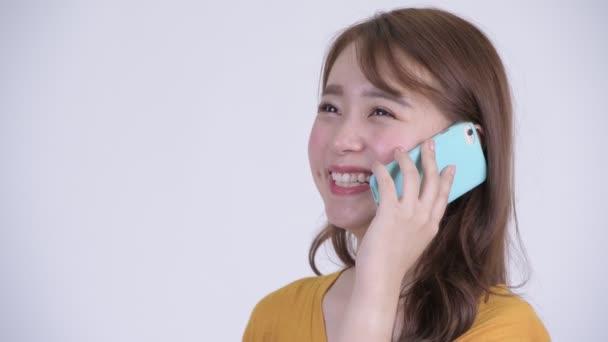 Mutlu genç güzel Asyalı kadın telefonda konuşurken yüzünü — Stok video