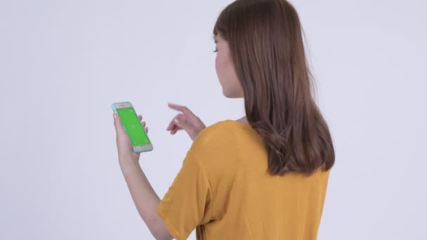 Vue arrière de heureuse jeune femme asiatique en utilisant le téléphone — Video