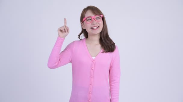 Unga glada asiatiska nörd kvinna pekar uppåt — Stockvideo