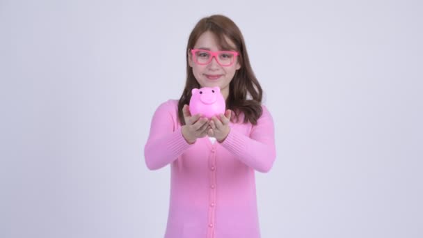 Jonge gelukkig Aziatische nerd vrouw geven piggy bank — Stockvideo