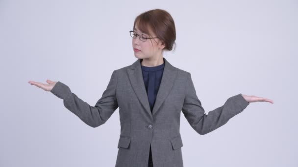 Молодая счастливая азиатская бизнесвумен сравнивает что-то — стоковое видео