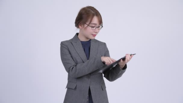 Молодая счастливая азиатская бизнесвумен показывает планшет и показывает большие пальцы вверх — стоковое видео