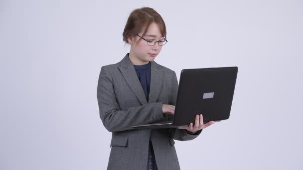 Jovem feliz mulher de negócios asiática pensando ao usar laptop — Vídeo de Stock