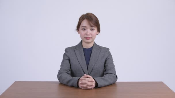 Young happy Asian businesswoman smiling behind desk — Stock Video