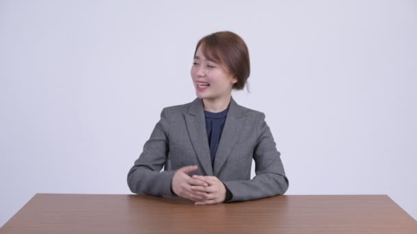 Joven feliz mujer de negocios asiática presentando algo en el escritorio — Vídeo de stock