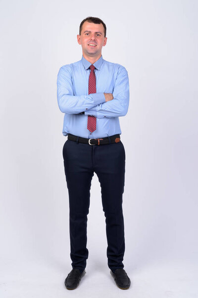 Full body shot of happy businessman smiling with arms crossed