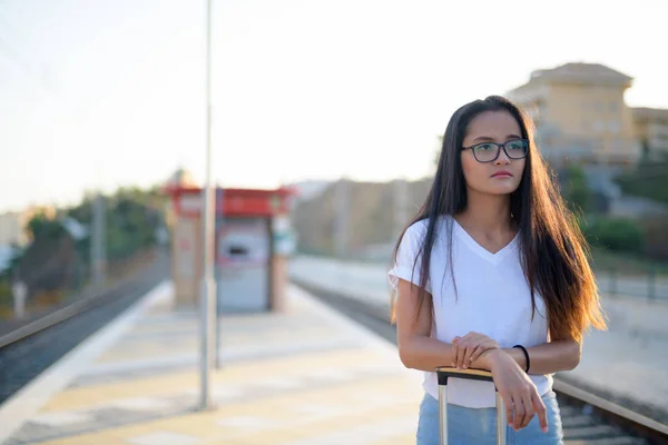 Молодая красивая азиатская туристка думает на вокзале — стоковое фото