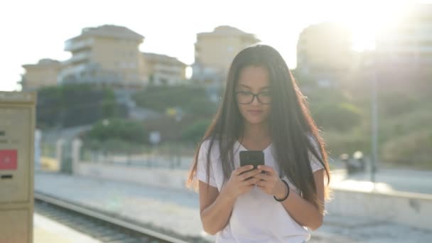 Jonge gelukkig Aziatische toeristische vrouw met behulp van de telefoon terwijl we wachten op het treinstation — Stockvideo